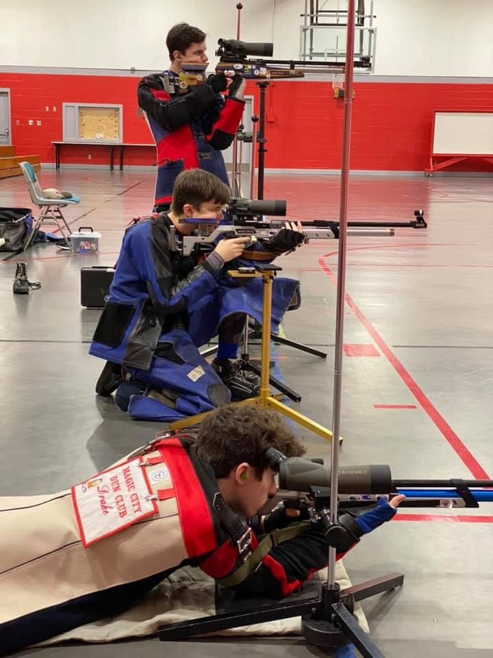 Three Heritage Christian rifle athletes demonstrating prone, standing, and kneeling positions